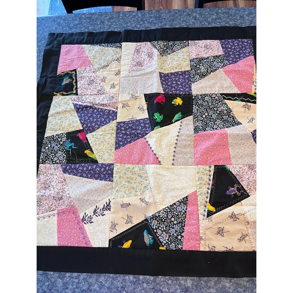 Black quilted wall hanging featuring colorful frogs 29x29